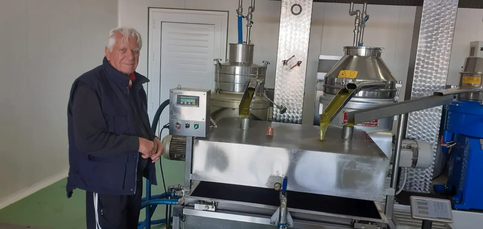 Ευάγγελος (Angelo) beside the press as fresh olive oil streams out