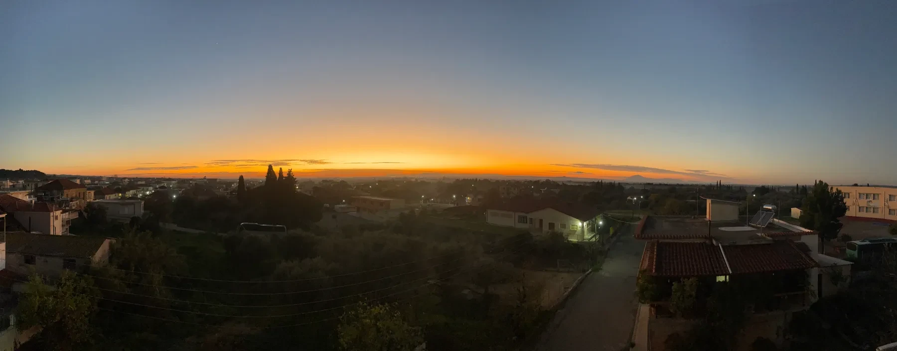 A wide panorama of the village at dawn, warm light on the horizon